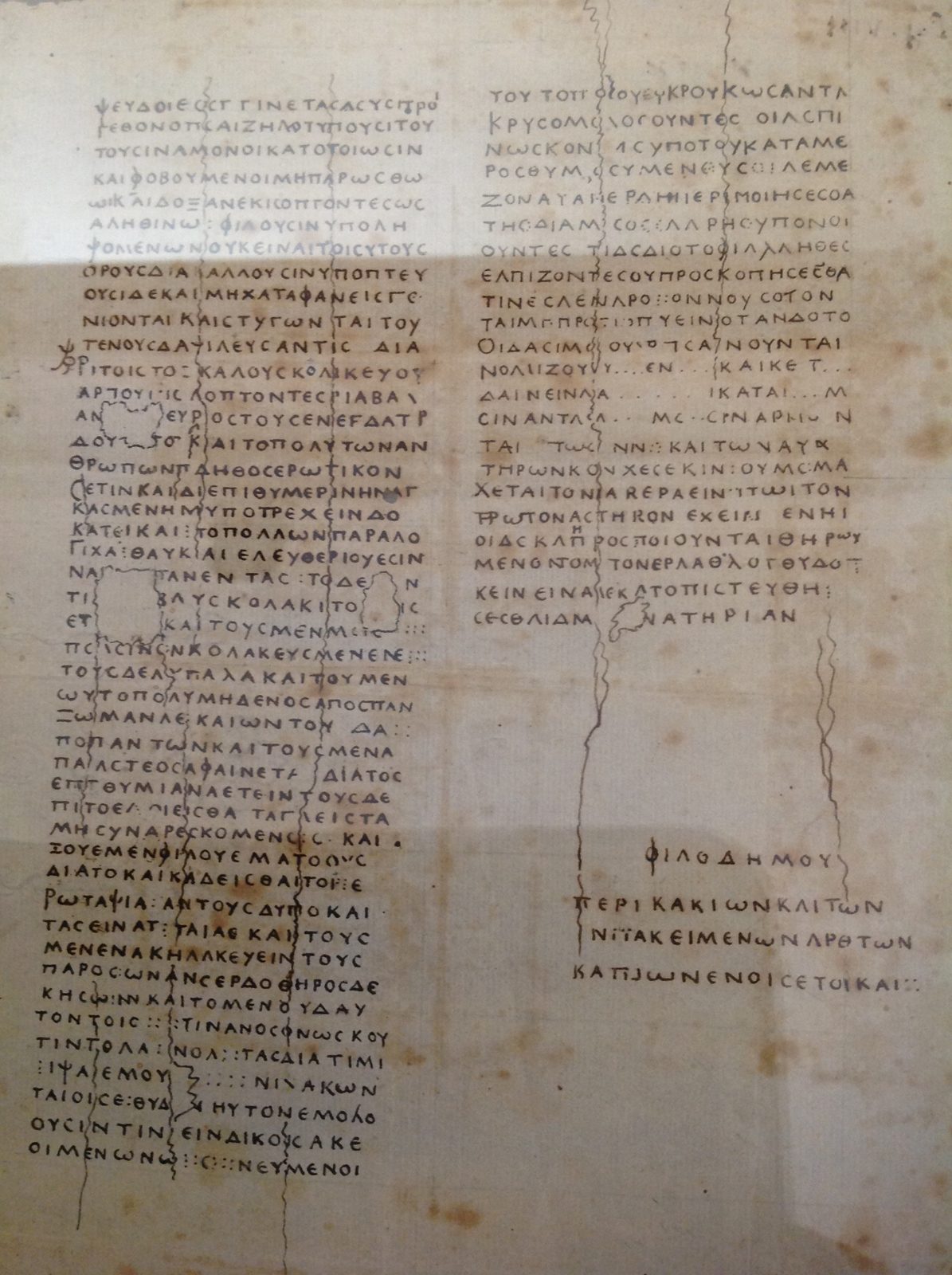 A historic hand-drawn copy of two columns of Greek, with the title of the work at the bottom right