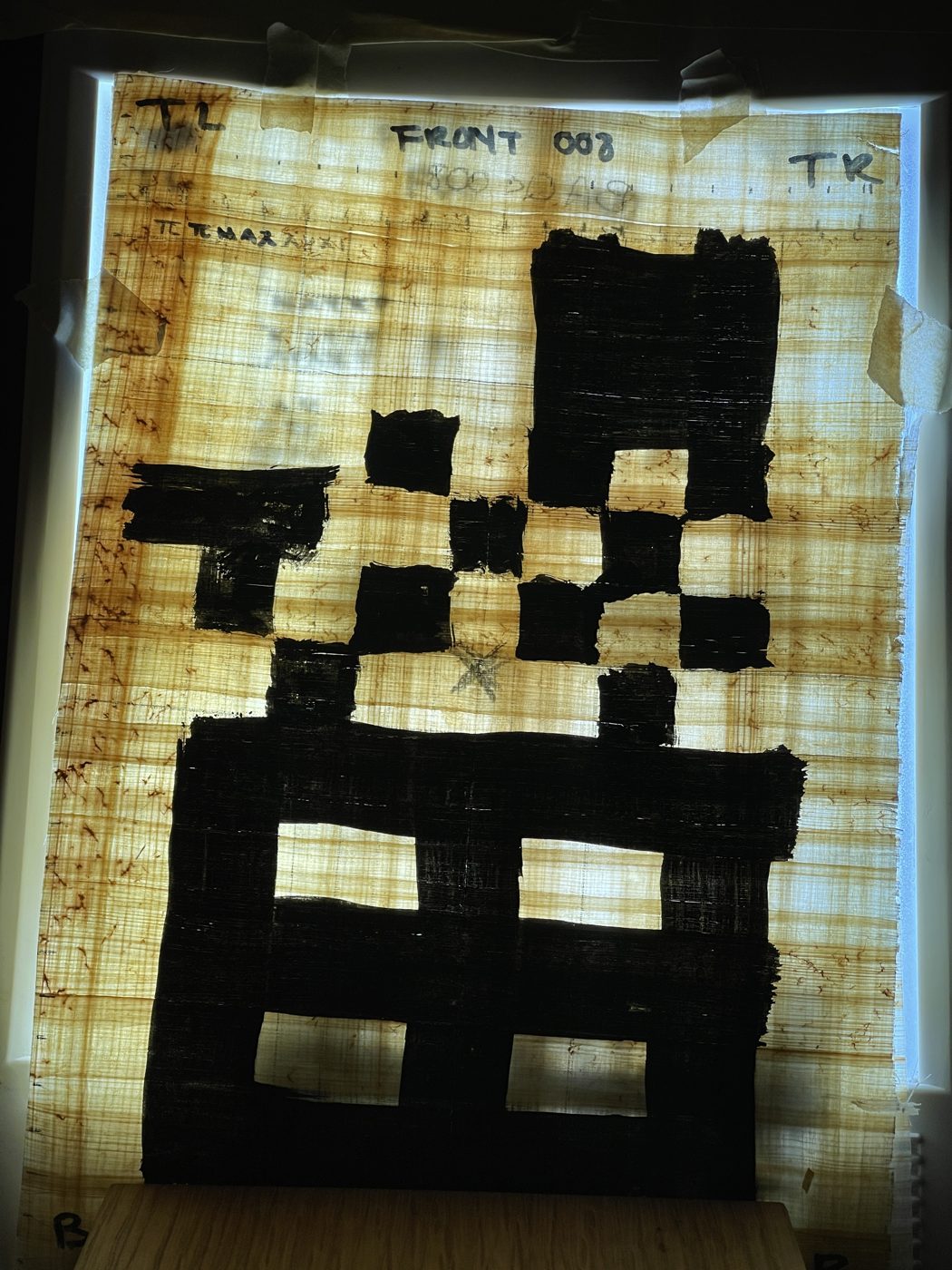 Backlit papyrus sheet with a big ink checkerboard