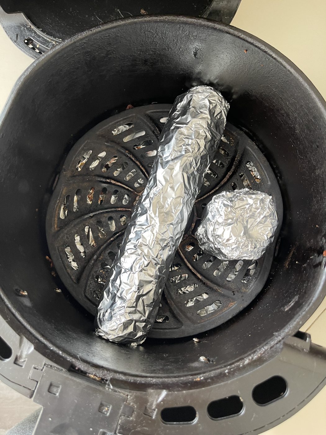 A foil-wrapped scroll in an air fryer basket