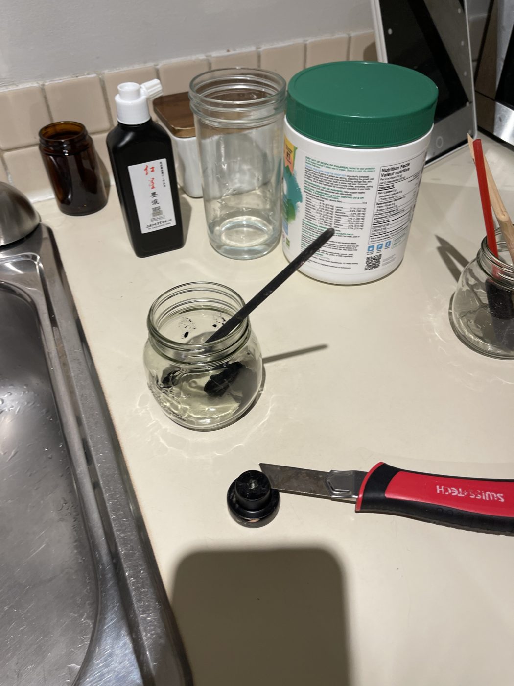 Ink bottle, jars and a brush by the sink
